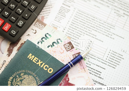 Mexican pesos money bills in big amount lies on table with pen, calculator, passport and tax forms Mexican pesos money bills in big amount lies on table with pen, calculator, passport and tax forms 126829459