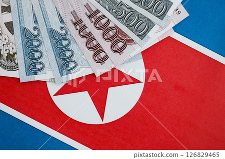 North Korean won money bills in big amount lies on People Republic of Korea flag close up North Korean won money bills in big amount lies on People Republic of Korea flag close up 126829465