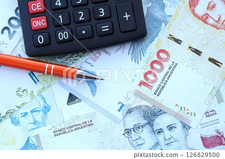 Argentine pesos money bills in big amount lies on table with pen and calculator close up 126829500