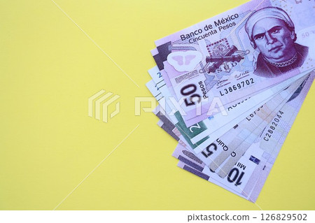 Mexican pesos money bills in big amount lies on yellow color table close up 126829502