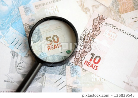 Brazilian reais banknotes and magnifying glass. The current Brazil real money bills and loupe 126829543