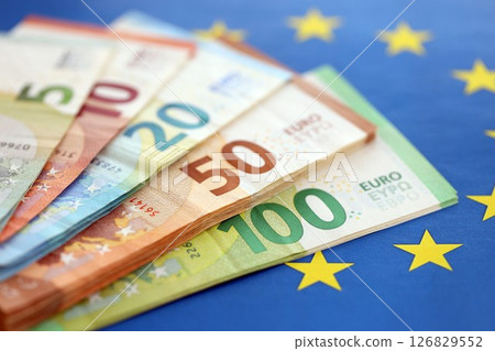 European eur currency money bills on Euro union blue flag close up European eur currency money bills on Euro union blue flag close up 126829552
