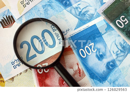 Israel New Shekels banknotes and magnifying glass. The current Israel money bills with loupe Israel New Shekels banknotes and magnifying glass. The current Israel money bills with loupe 126829563