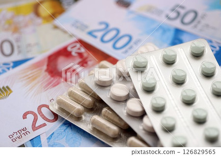 Israel New Shekels banknotes and medicine pills. The current Israel money bills and drugs Israel New Shekels banknotes and medicine pills. The current Israel money bills and drugs 126829565