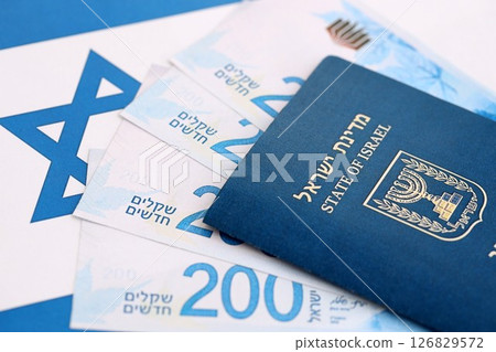 Israel New Shekels banknotes and passport on flag. The current Israel money bills and pass 126829572