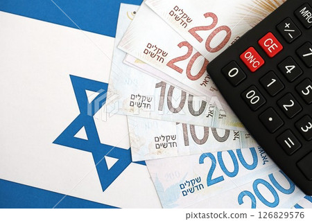 Israel New Shekels banknotes and calculator on flag. The Israel money bills and calc lies on flag 126829576