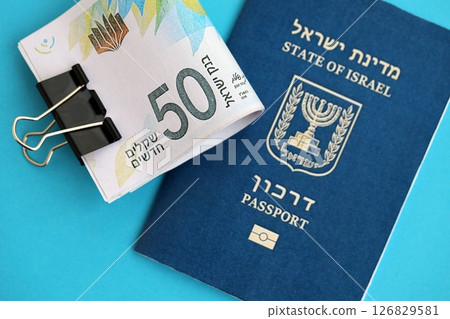 Israel New Shekels banknotes and passport on blue background. The current Israel money bills 126829581