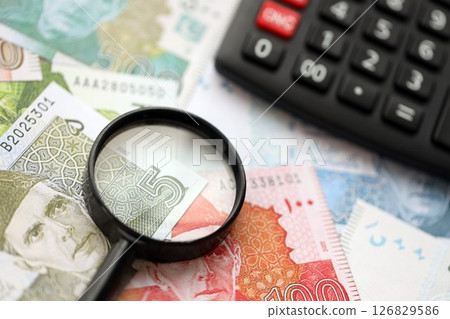 Pakistan rupees banknotes and calculator with magnifying glass. Pakistan money bills calc with loupe Pakistan rupees banknotes and calculator with magnifying glass. Pakistan money bills calc with loupe 126829586