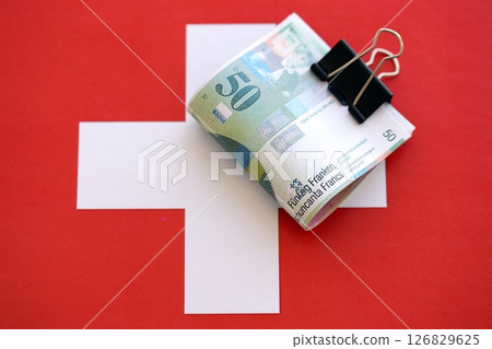 Swiss franc banknotes and flag. The francs money bills lies on flag in big amount Swiss franc banknotes and flag. The francs money bills lies on flag in big amount 126829625