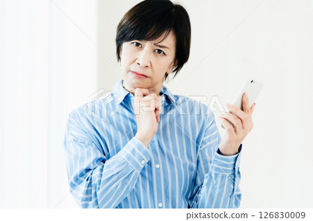 一位中年婦女拿著智慧型手機 126830009