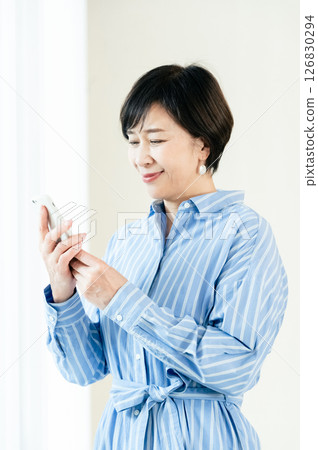 A middle-aged woman who operates a smartphone A middle-aged woman who operates a smartphone 126830294