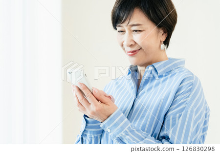 A middle-aged woman who operates a smartphone 126830298