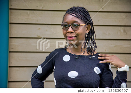 Confident African Woman Wearing Polka Dot Sweater and Glasses Outdoors Confident African Woman Wearing Polka Dot Sweater and Glasses Outdoors 126830407