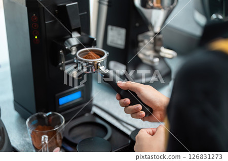 Coffee Grinding and Precision Measurement. A skilled barista measuring coffee grounds with precision. Coffee Grinding and Precision Measurement. A skilled barista measuring coffee grounds with precision. 126831273