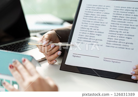 Real estate agent highlighting signature sections on a contract during a client meeting. 126831389