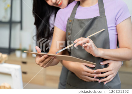 LGBTQ couple embracing while painting, showcasing love and creativity LGBTQ couple embracing while painting, showcasing love and creativity 126831392