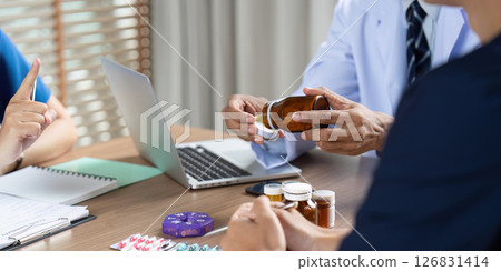 Team Doctor and Meeting. A doctor discussing medication with colleagues during a professional meeting. 126831414