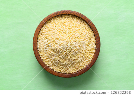 Yellow millet grain in wooden bowl on green background, Food ingredient, Top view 126832298