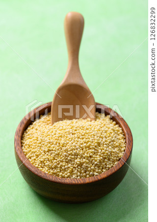 Yellow millet grain in wooden bowl with scoop on green background, Food ingredient Yellow millet grain in wooden bowl with scoop on green background, Food ingredient 126832299