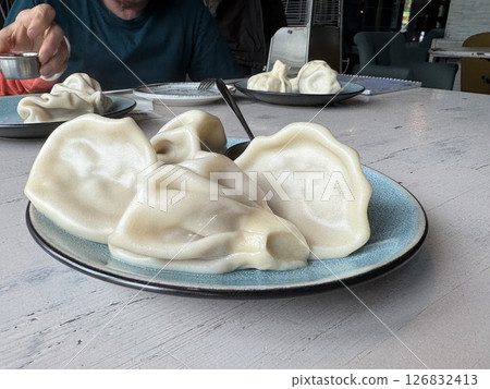 traditional georgian dish khinkali lies on a plate with sauce in a restaurant. High quality photo traditional georgian dish khinkali lies on a plate with sauce in a restaurant. High quality photo 126832413