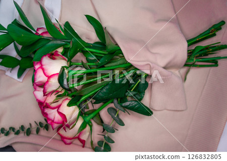 A bouquet of roses is wrapped in a coarse knit woolen sweater. 126832805