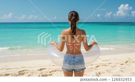 Back view of a woman holding a swim ring on the beach 126832953