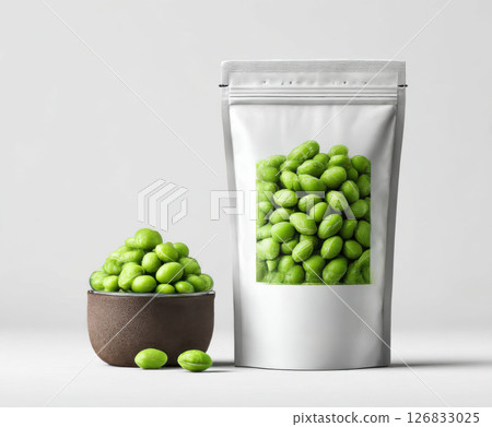 Edamame beans in ceramic bowl next to zip lock packaging bag on white background 126833025