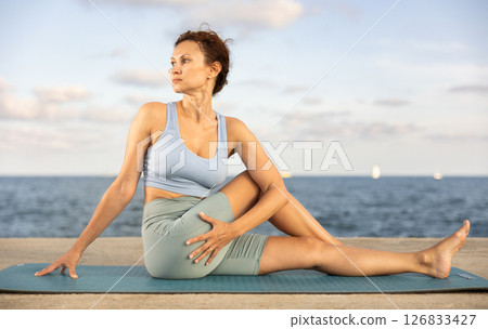Woman performing Ardha Matsyendrasana position yoga training Woman performing Ardha Matsyendrasana position yoga training 126833427