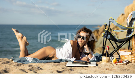 Desirable woman lying on blanket near coastline 126833429