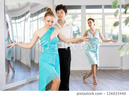 Dance teacher teaches a girl and a boy couples ballroom dancing Dance teacher teaches a girl and a boy couples ballroom dancing 126833440