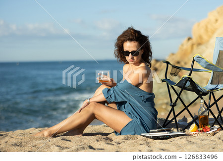 Seductive businesswoman drinking whiskey near shoreline 126833496