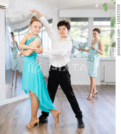 Teenage girl and boy practicing waltz in dance hall with female mentor Teenage girl and boy practicing waltz in dance hall with female mentor 126833508