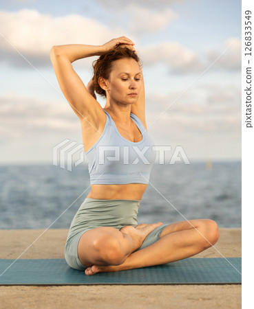 Yoga practice on embankment, female athlete fulfil carry out padmasana svastikasana, Siddhasana 126833549