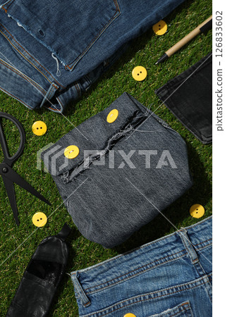 Denim bag and jeans on green background, top view 126833602