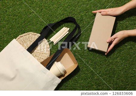Cotton bag and box in hands on green background, top view Cotton bag and box in hands on green background, top view 126833606