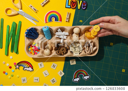 Art supplies in egg tray and hand on yellow background, top view Art supplies in egg tray and hand on yellow background, top view 126833608