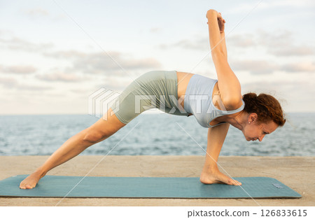 Yoga practice on embankment, female athlete fulfil carry out elongated side angle 126833615