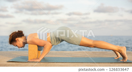 Yoga practice on embankment, female athlete fulfil carry out ashtangasana with blocks Yoga practice on embankment, female athlete fulfil carry out ashtangasana with blocks 126833647