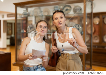 Young woman with teen daughter walk around museum, cookware zone. 126833656
