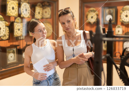 Young woman with teen daughter walk around museum, view clock Young woman with teen daughter walk around museum, view clock 126833719