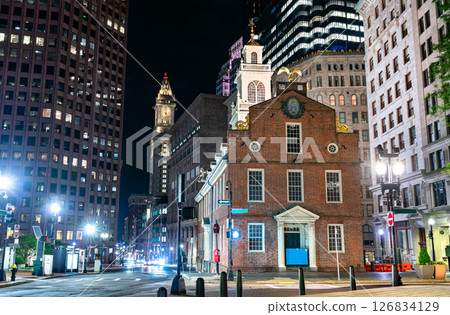 Night view of the historic Old State House in Boston, Massachusetts, surrounded by modern skyscrapers and softly illuminated streetlights. The colonial-era building stands out with its red brick 126834129