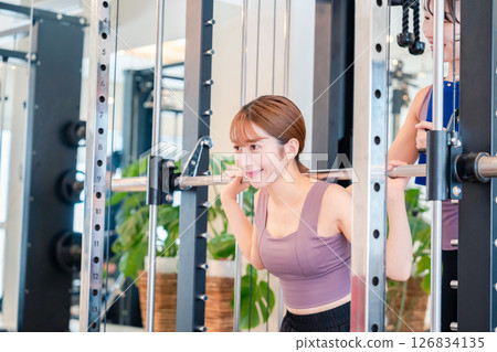 A woman doing muscle training under the guidance of a female trainer 126834135