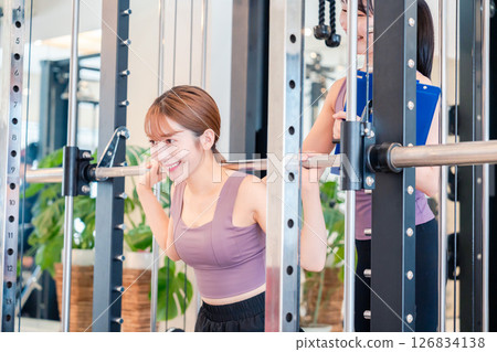 A woman doing muscle training under the guidance of a female trainer A woman doing muscle training under the guidance of a female trainer 126834138