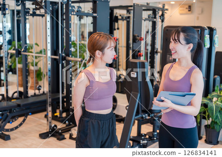 A woman doing muscle training under the guidance of a female trainer A woman doing muscle training under the guidance of a female trainer 126834141