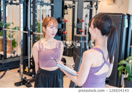 A woman doing muscle training under the guidance of a female trainer A woman doing muscle training under the guidance of a female trainer 126834143