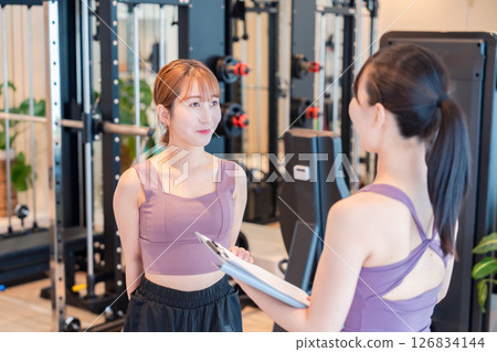 A woman doing muscle training under the guidance of a female trainer A woman doing muscle training under the guidance of a female trainer 126834144