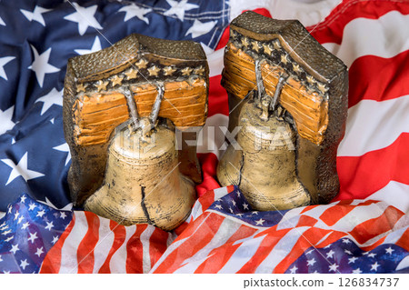Liberty bells displayed against an American flag, symbolizing patriotism during celebrations, national holidays. Liberty bells displayed against an American flag, symbolizing patriotism during celebrations, national holidays. 126834737