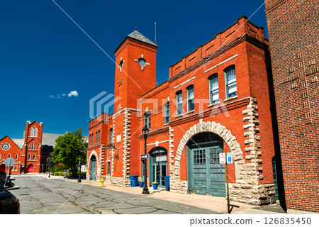 A red brick fire station building in Pittsfield, Massachusetts, USA with arched stone doorways and a central tower stands under a deep blue sky 126835450