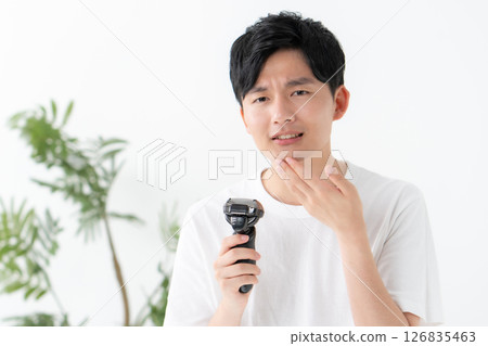 Man shaving his beard with a shaver 126835463