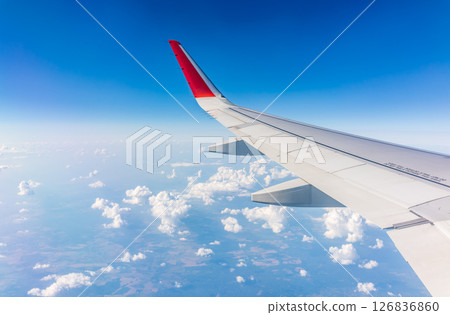 View from the airplane window at a beautiful cloudy sky and the airplane wing 126836860
